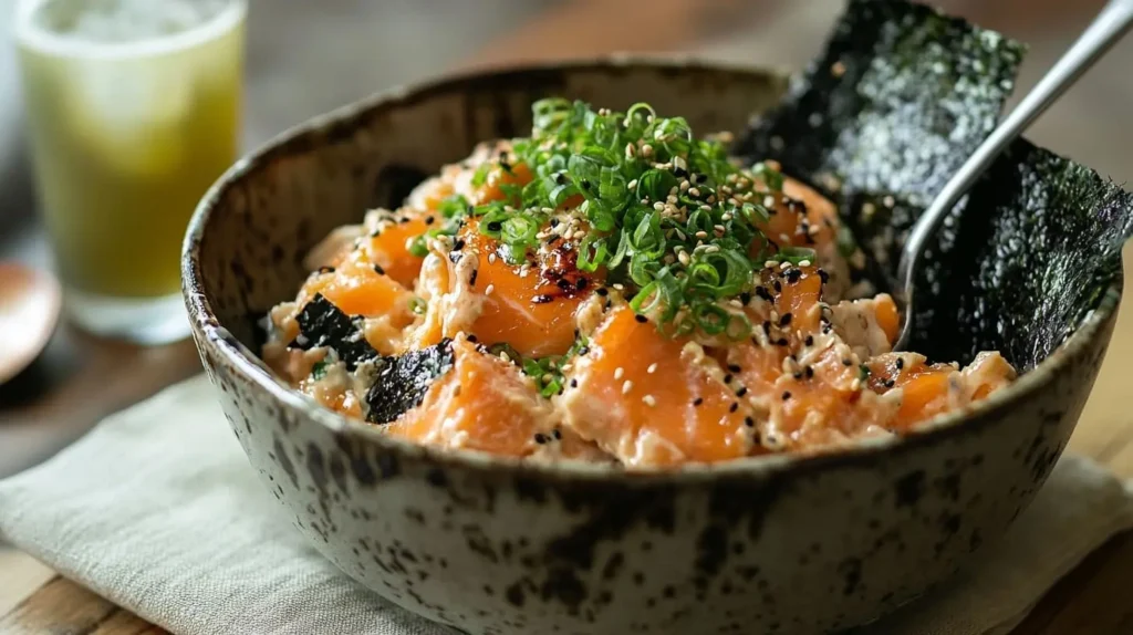 Salmon sushi bake served in a bowl with nori sheets, garnished with furikake and sriracha.